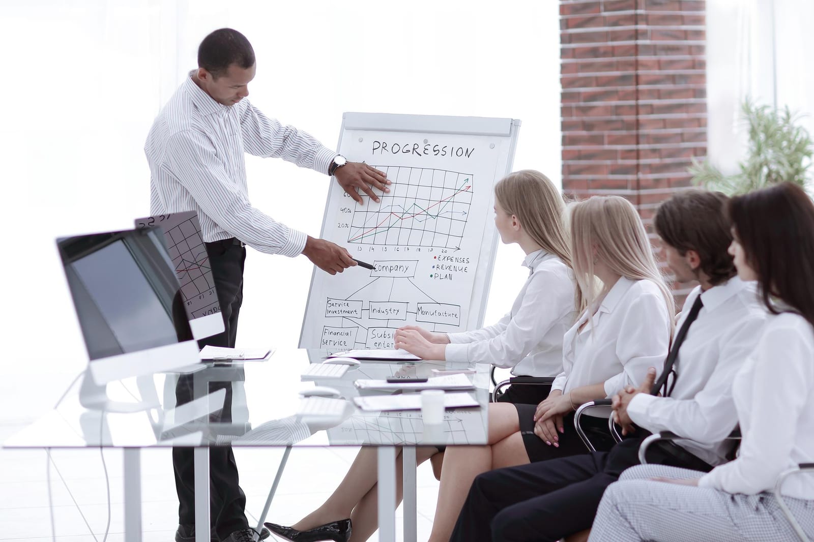 Instrutor apresenta um gráfico de progressão em flipchart para um grupo de participantes sentados